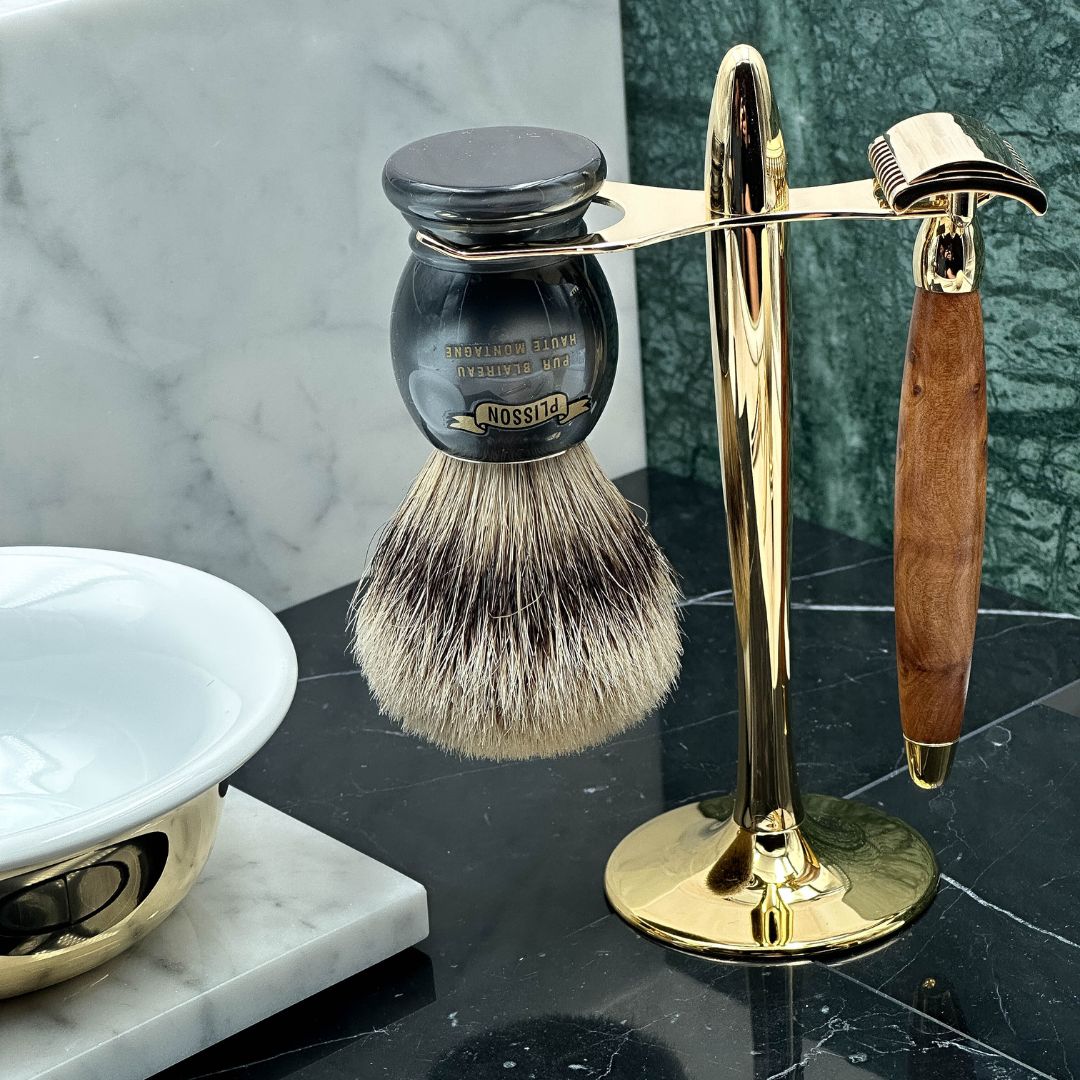 Razor and shaving brush on stand with bowl on marble background
