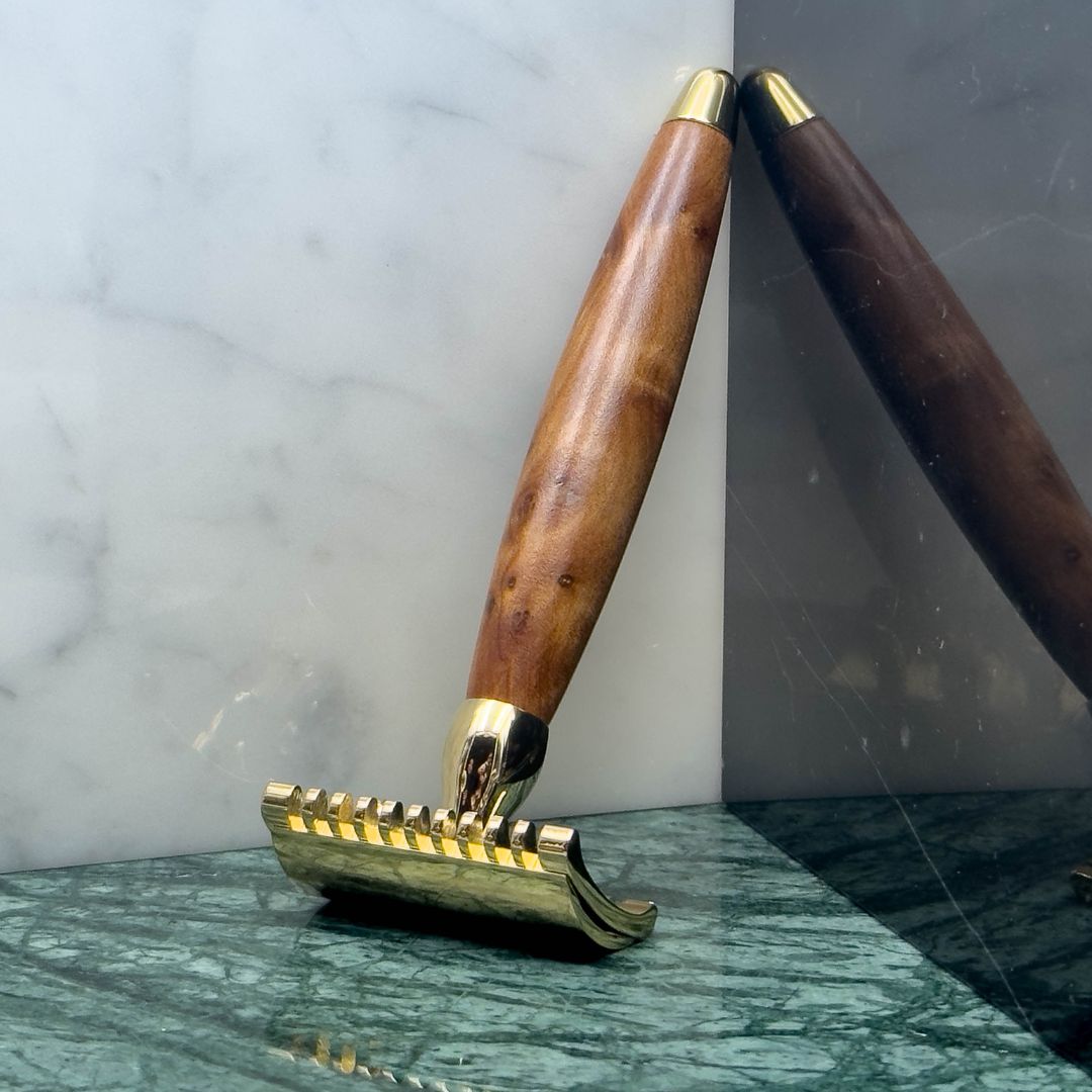 Razor Plisson gold and wood handle on marble with reflection